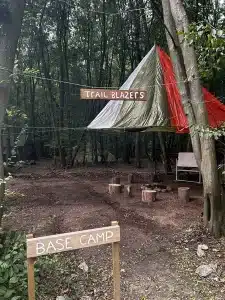 The Trail Blazers base camp area with wooden logs as seats and a large tarpaulin covering the area