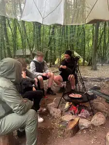 A Trail Blazers staff member sat on a lop at a camp fire talking to three boys