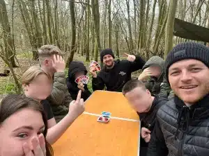Three Trail Blazers staff members and five boys sat round a table in the woods playing Uno