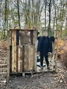Two boys stood inside a partially constructed wooden hut in the woods