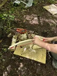A person using a tool to start a fire on some wood