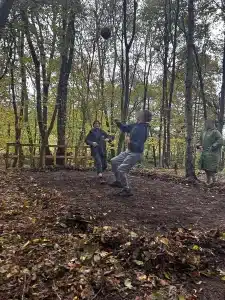 Two boys playing football in the woods with one boy looking up at the ball high in the air