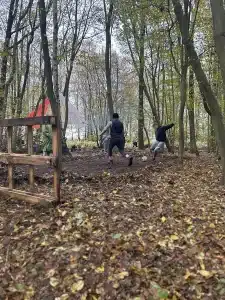 Two boys playing football in the woods as one boy goes to take a shot