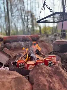 Five tins of soup sat round the edge of an open fire