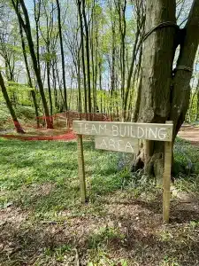 A sign in the woods saying 'Team Building Area'