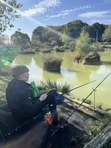A boy sat fishing at the edge of a lake