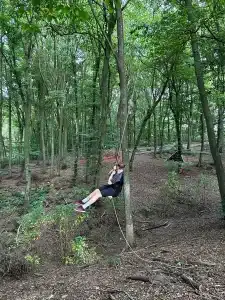 A boy swinging on a rope swing in the woods