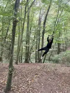 A boy swinging on a rope swing in the woods