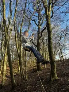A boy swinging on a rope swing in the woods