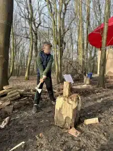 A boy about to swing an axe onto a piece of wood on a log